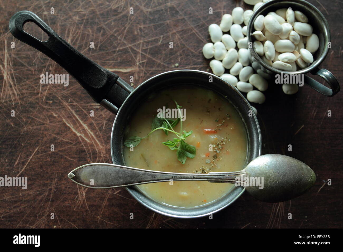 Angolo di visione sulla minestra di fagioli in una piccola pentola con un cucchiaio Foto Stock
