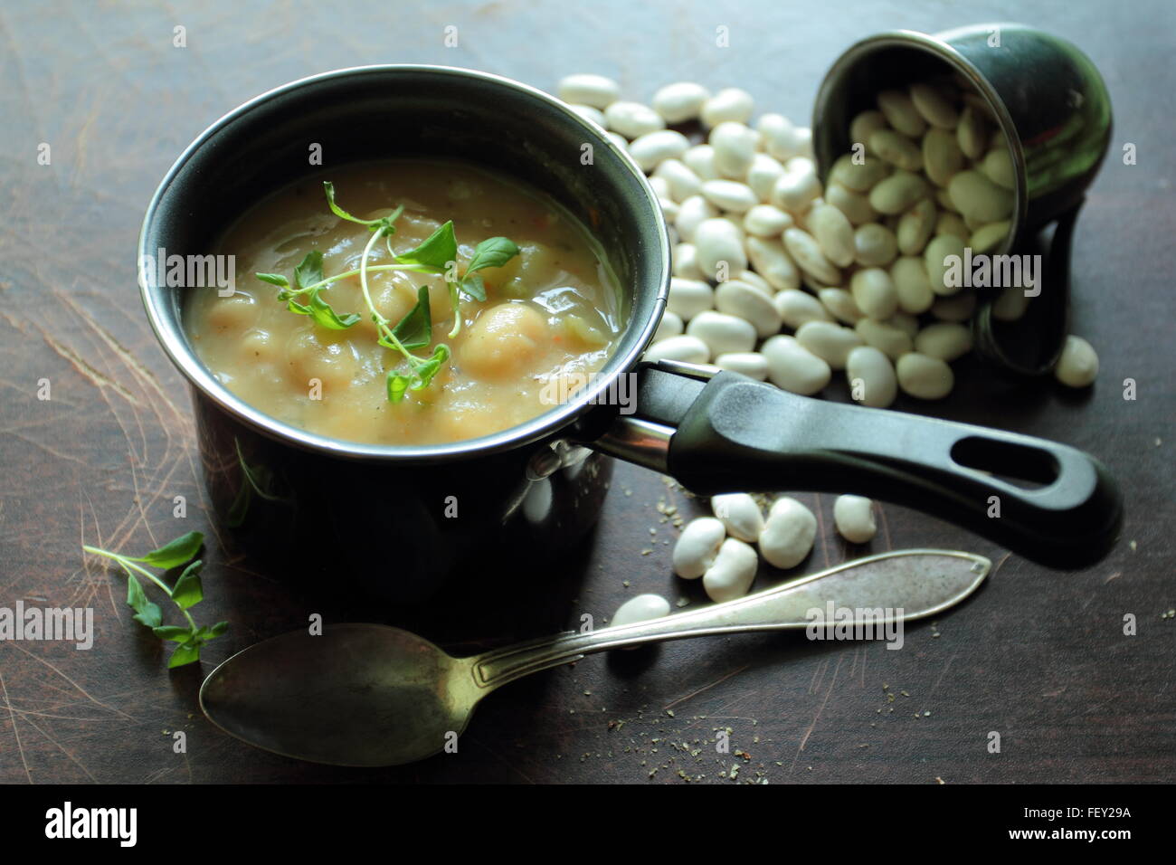 Piccolo vaso con zuppa di fagioli con un cucchiaio su un tavolo Foto Stock