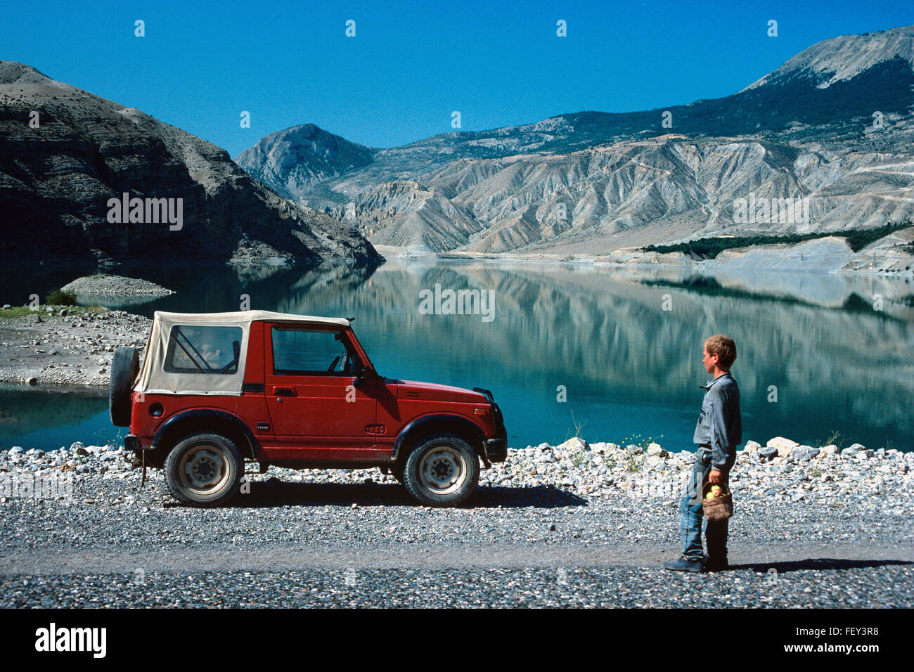 Un villaggio turco ragazzo si ammira un rosso Suzuki Santana Jeep parcheggiata da Tortum Lago, a nord-est della Turchia Foto Stock