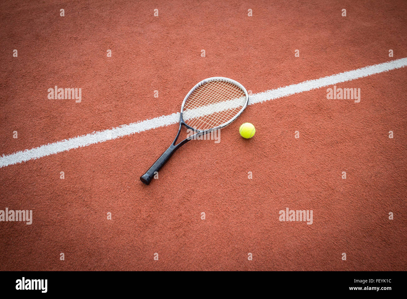 Racchetta da tennis nei pressi di una sfera gialla su un rosso mattone corte Foto Stock