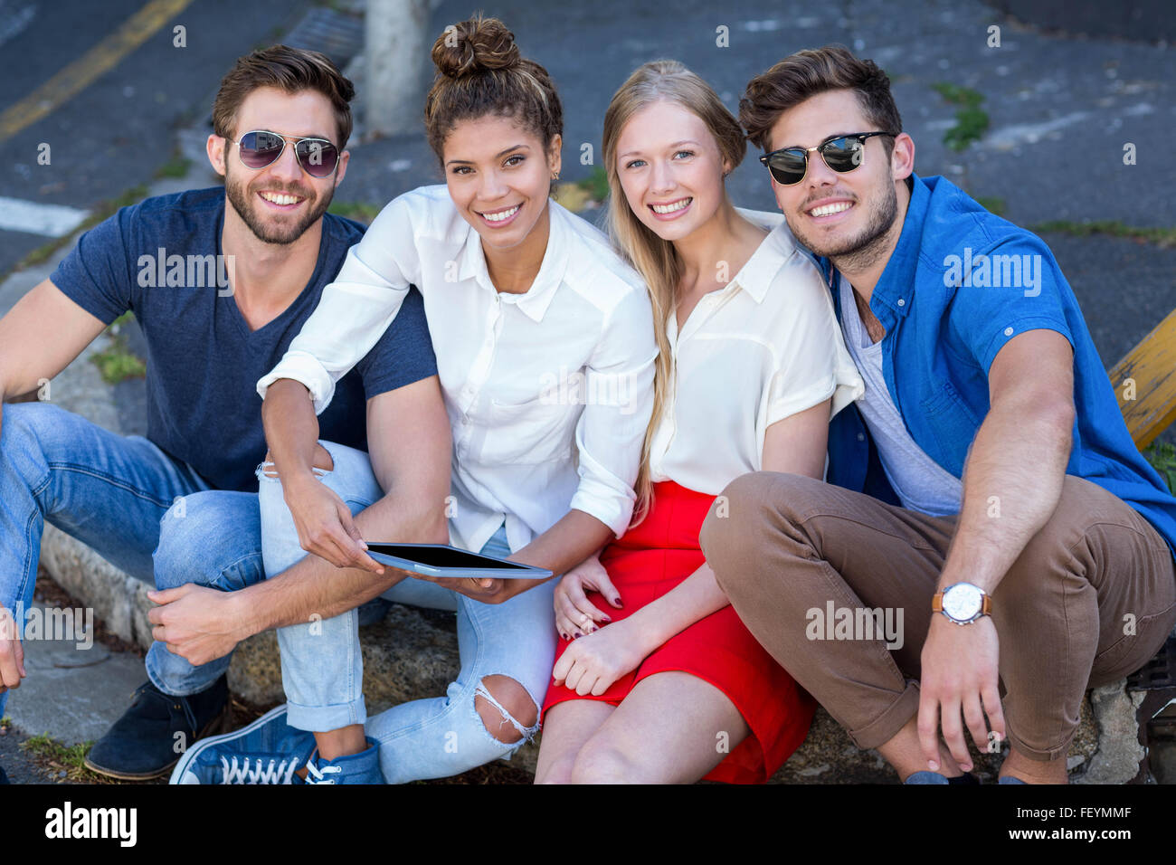 Hip amici guardando tablet e seduto sul marciapiede Foto Stock