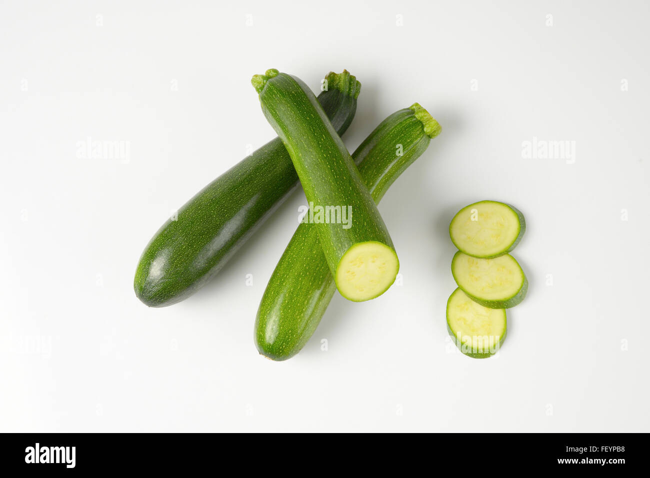 Intero e fette di zucchine su sfondo bianco Foto Stock