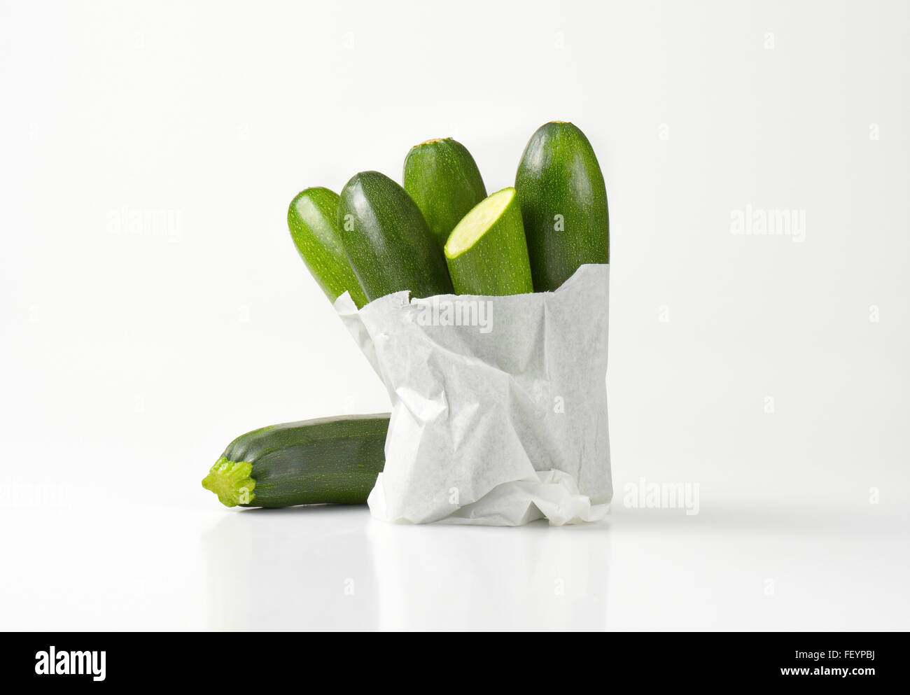 Borsa di baby zucchine su sfondo bianco Foto Stock