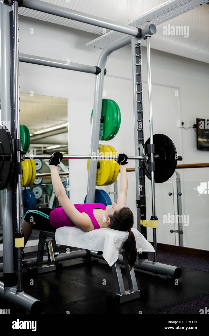 Montare la donna sollevando il barbell pressa da banco Foto Stock