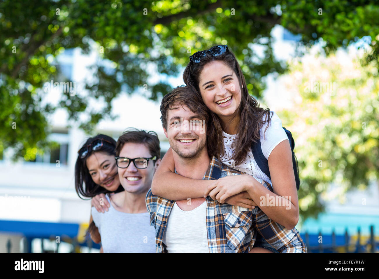 Hip uomini dando piggy back per le loro fidanzate Foto Stock