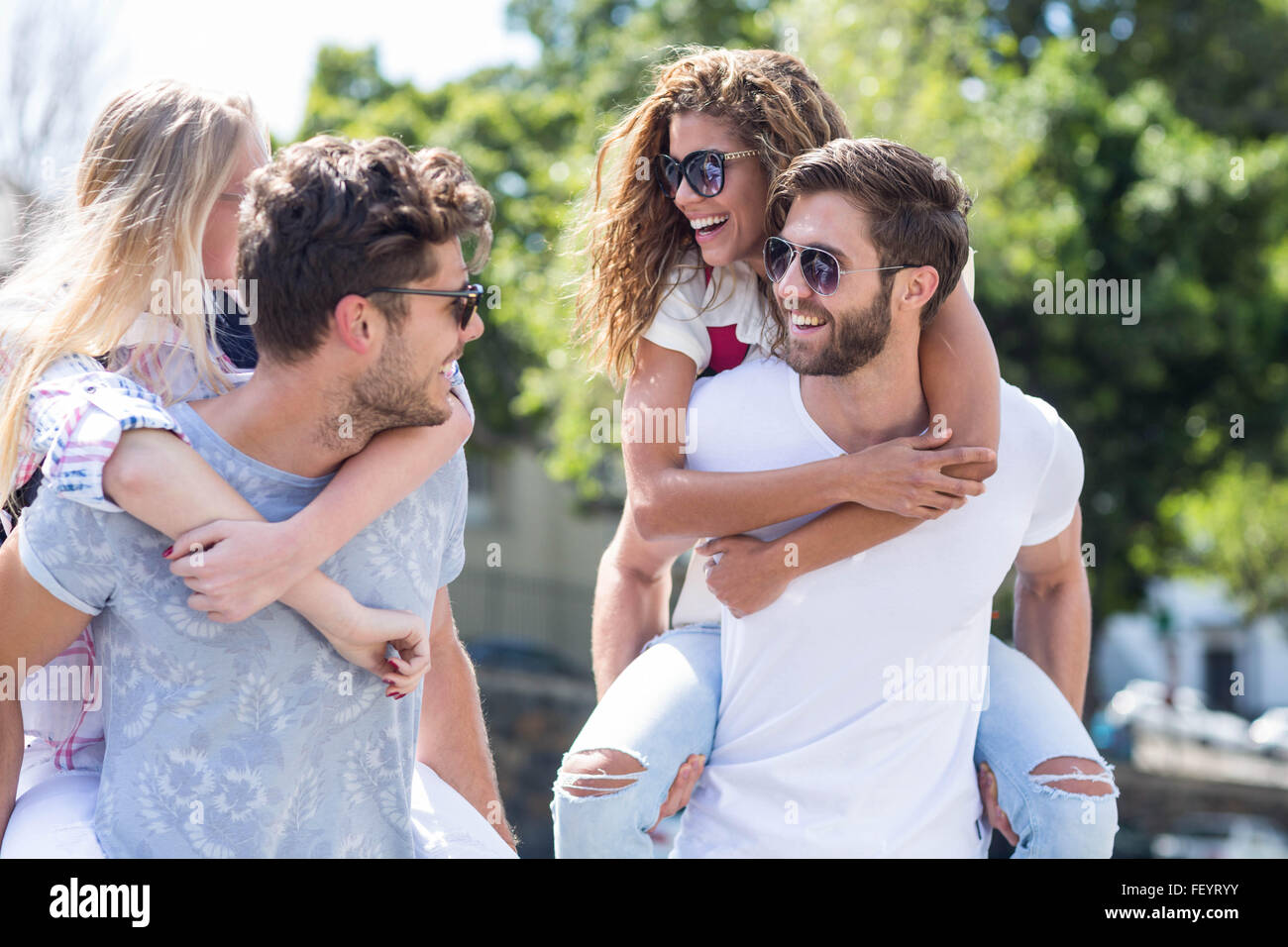 Hip uomini dando piggy back per le loro fidanzate Foto Stock