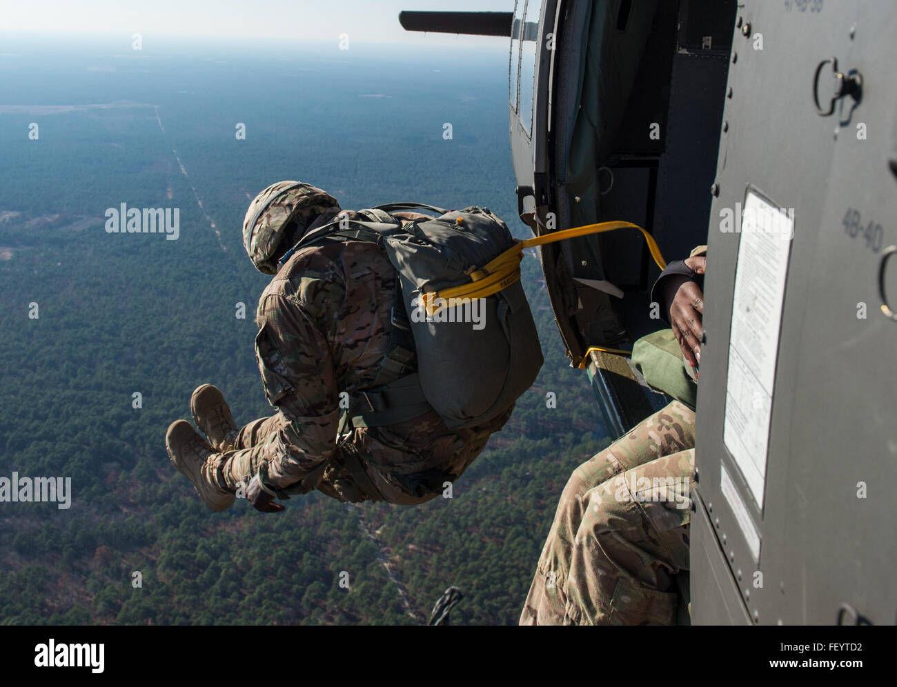 Un U.S. Soldato dell'esercito salta fuori da un UH-60 Black Hawk durante la diciottesima edizione di Randy Oler Memorial il funzionamento del giocattolo Drop, ospitato dalla U.S. Esercito degli affari civili e le operazioni psicologiche il comando (Airborne) a Camp Mackall, N.C., 8 dicembre, 2015. Il funzionamento del giocattolo Drop è la più grande del mondo di combinata airborne operazione che fornisce i paracadutisti da Stati Uniti e sette paesi partner l'opportunità di aiutare i bambini a ricevere giocattoli per le vacanze. Foto Stock