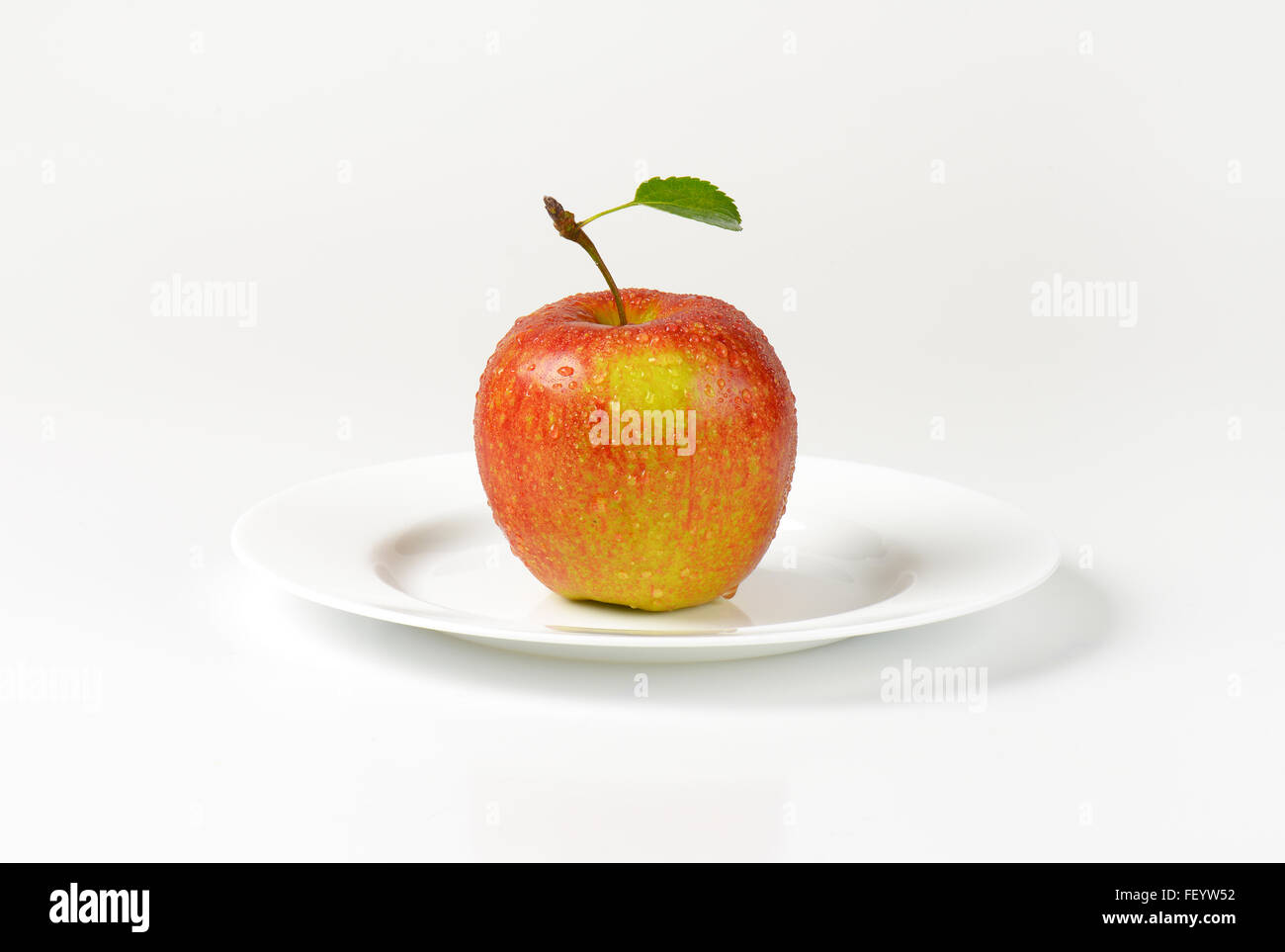 Si lava red apple con foglie sulla piastra bianca Foto Stock