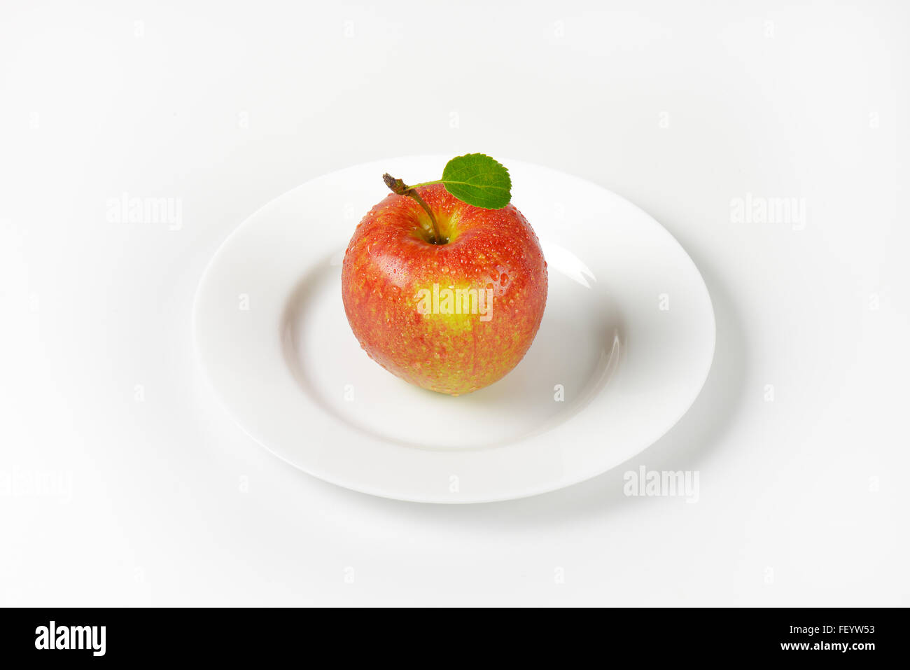 Si lava red apple con foglie sulla piastra bianca Foto Stock