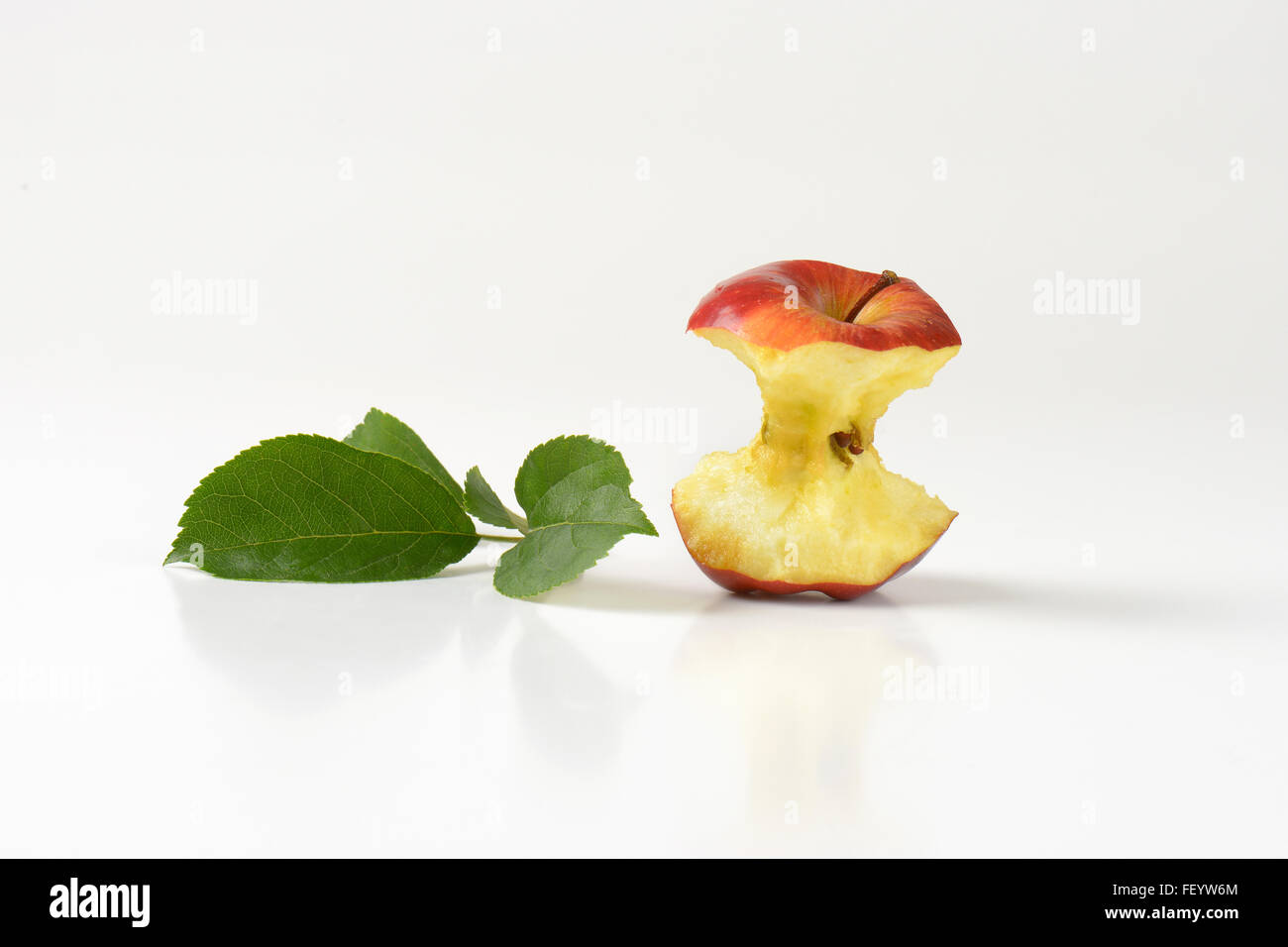 Apple core e foglie su sfondo bianco Foto Stock
