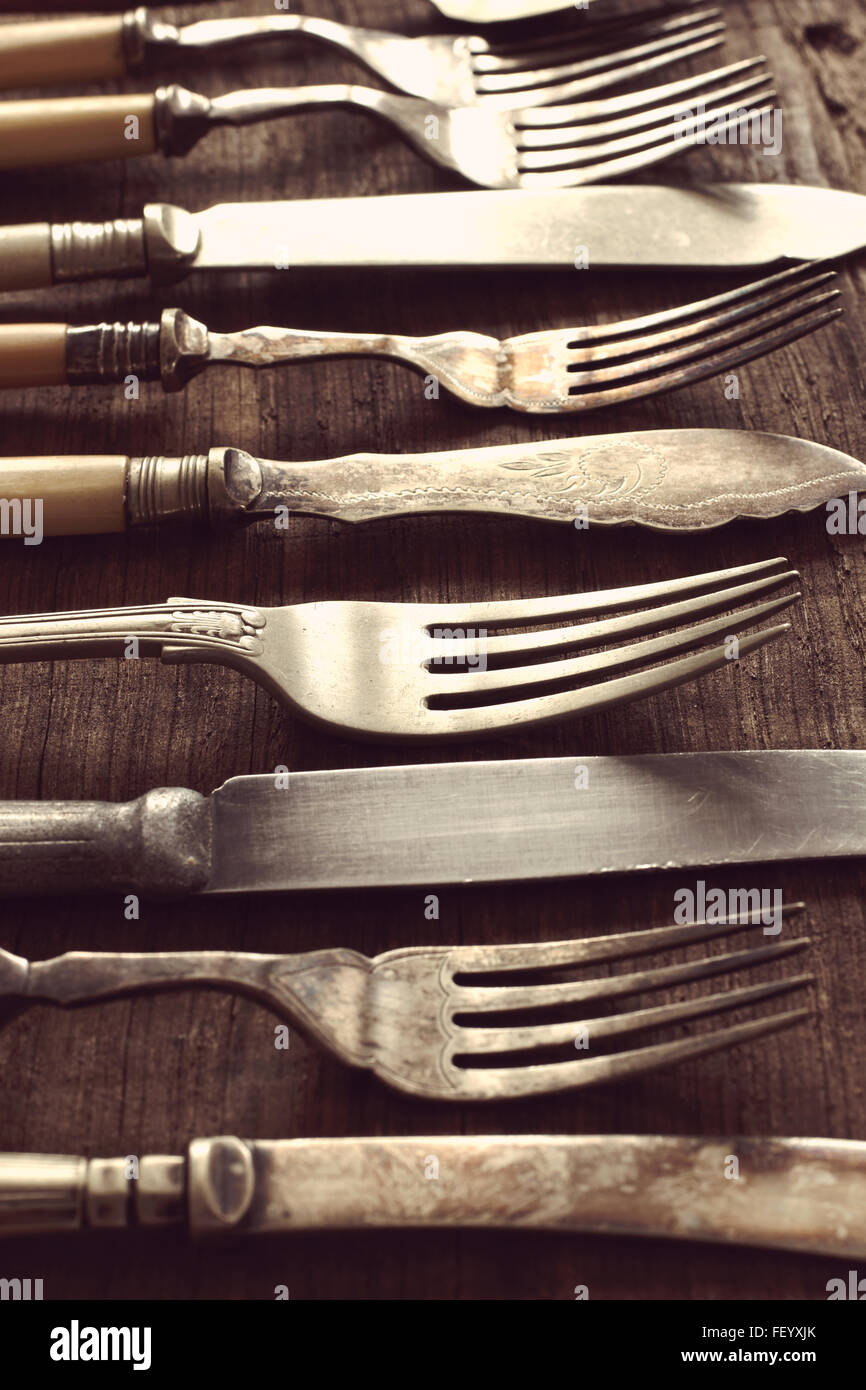 Vintage coltelli e forchette su un vecchio tavolo di legno shot con messa a fuoco poco profonde e vintage filtro applicato all'immagine Foto Stock