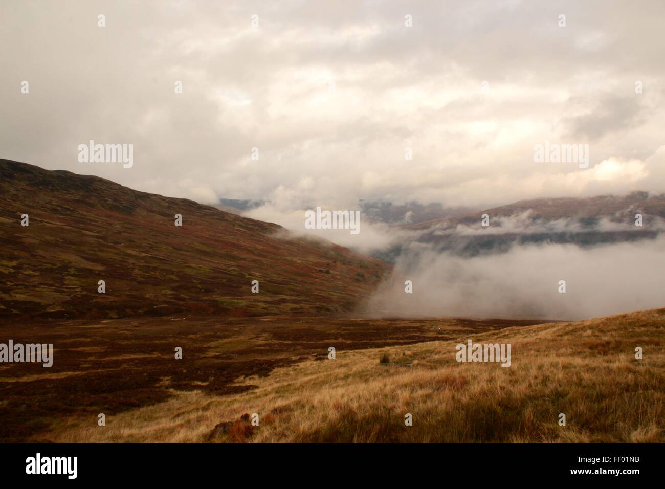 La nebbia lambisce i campi sulla strada fino alla sommità del ben vorlich con nuvole e altre montagne sullo sfondo Foto Stock