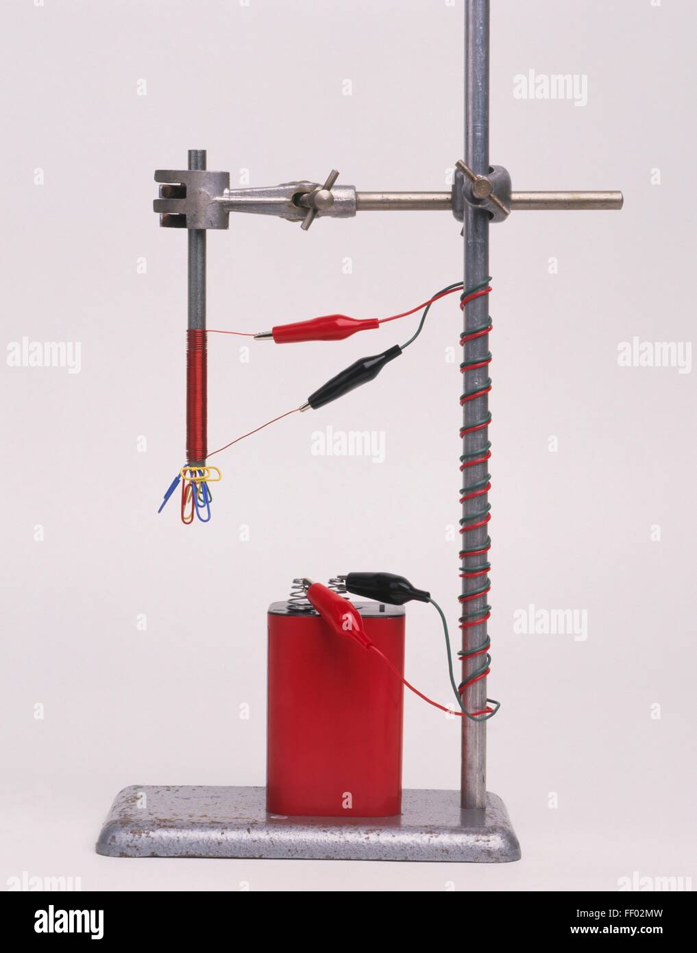 Esperimento elettromagnetico, batteria collegato ai fili sulla fascetta stand, sollevamento fermagli per carta Foto Stock
