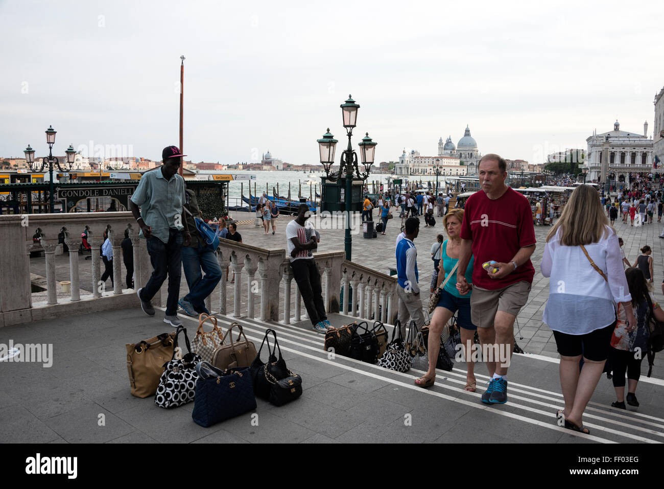 Un immigrato africano venditrice illegale di strada che vende borse da donna contraffatte come Gucci, Fendi e Prada a turisti in una zona turistica trafficata di Foto Stock