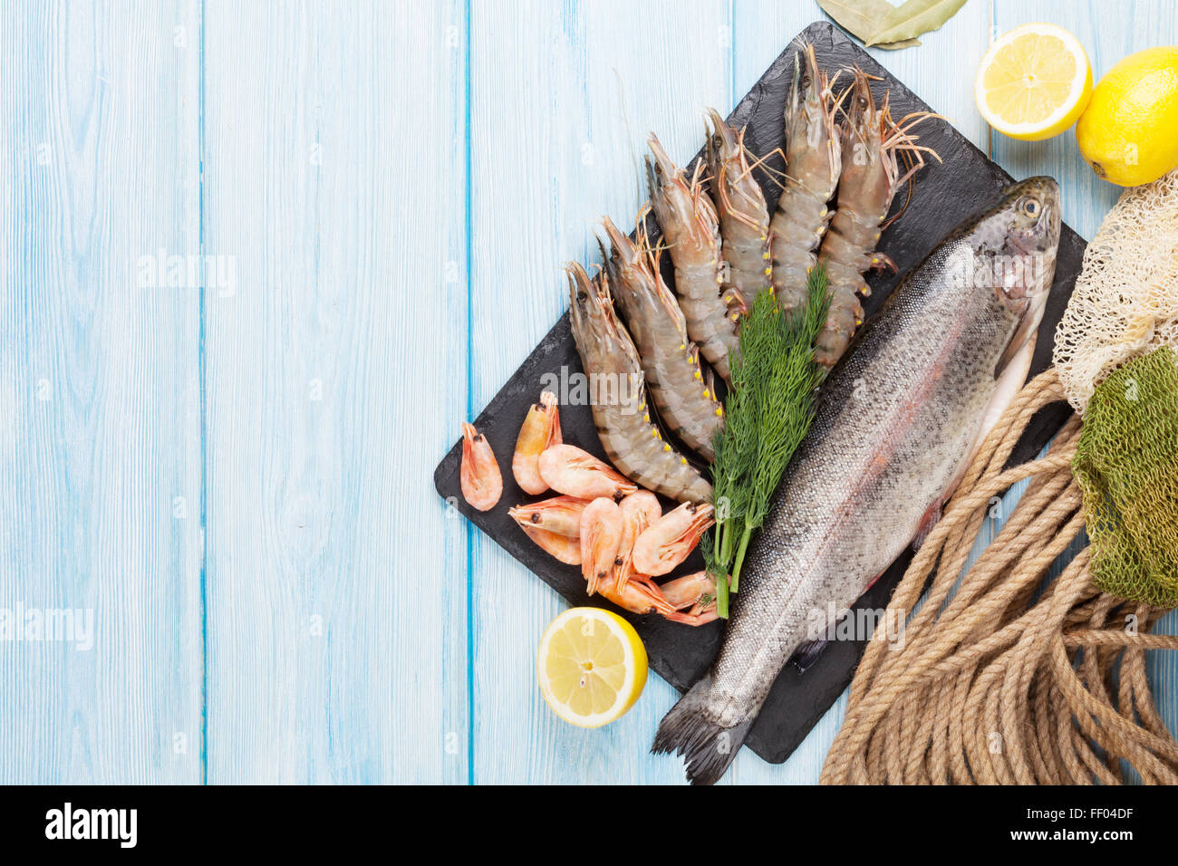 Crudo fresco il cibo del mare con spezie sulla lastra di pietra su un tavolo di legno dello sfondo. Vista da sopra con lo spazio di copia Foto Stock