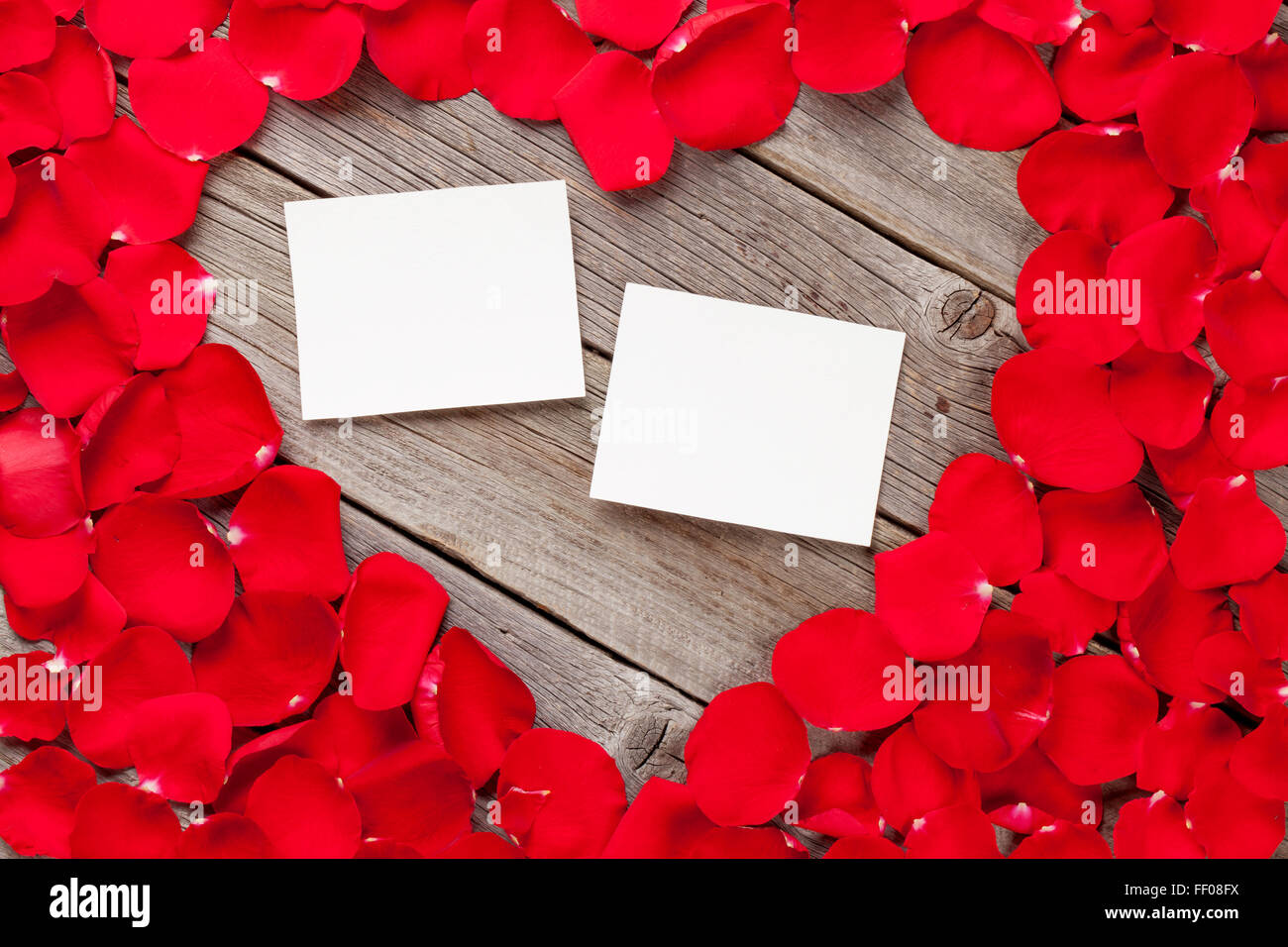Il giorno di San Valentino blank foto cornici di legno su sfondo rosso e petali di rosa Foto Stock