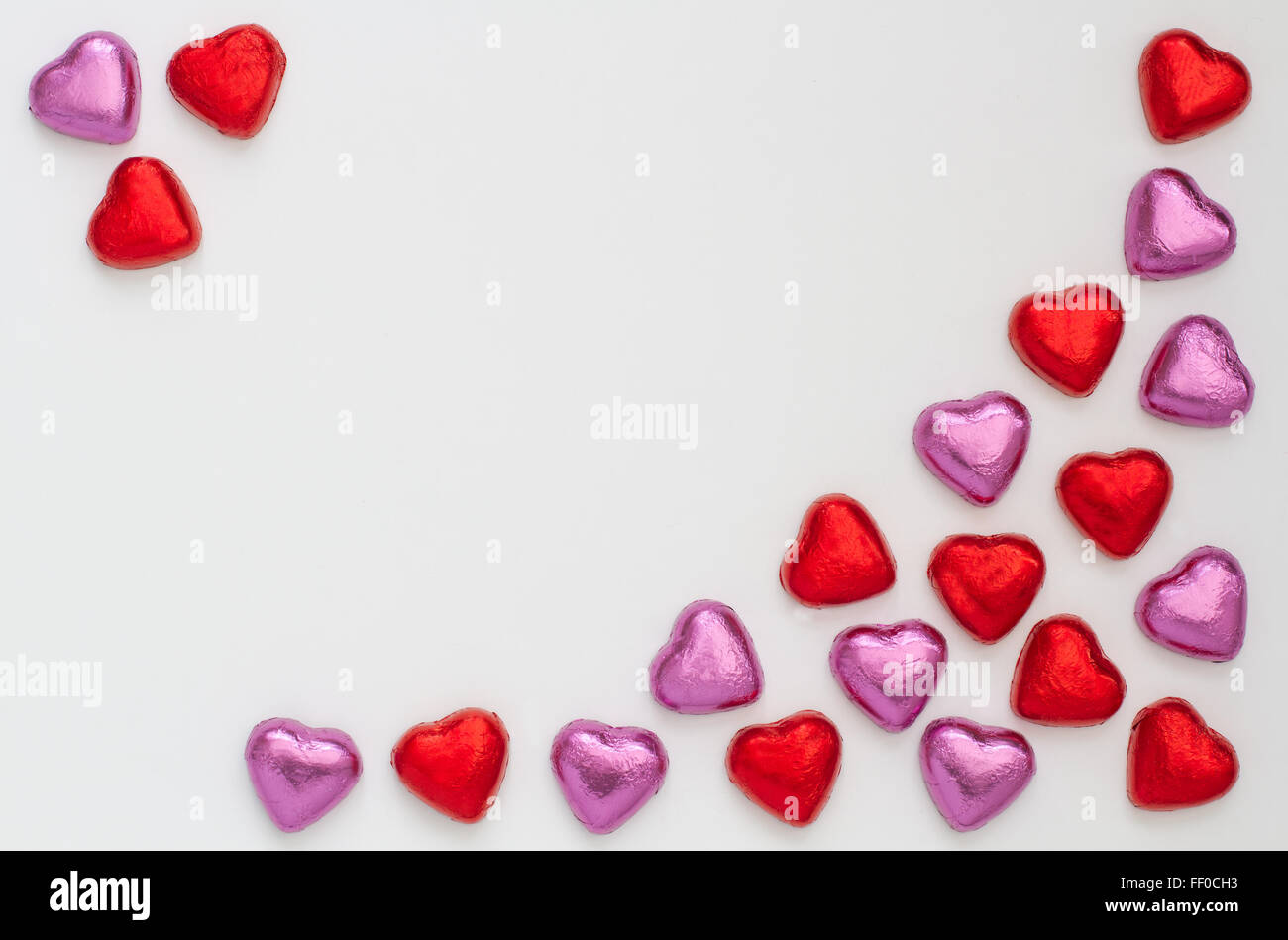 Cuore di cioccolato forme disposte su un isolato sfondo bianco per realizzare una cornice con copia spazio. rosso e rosa amore cuore candy. Foto Stock