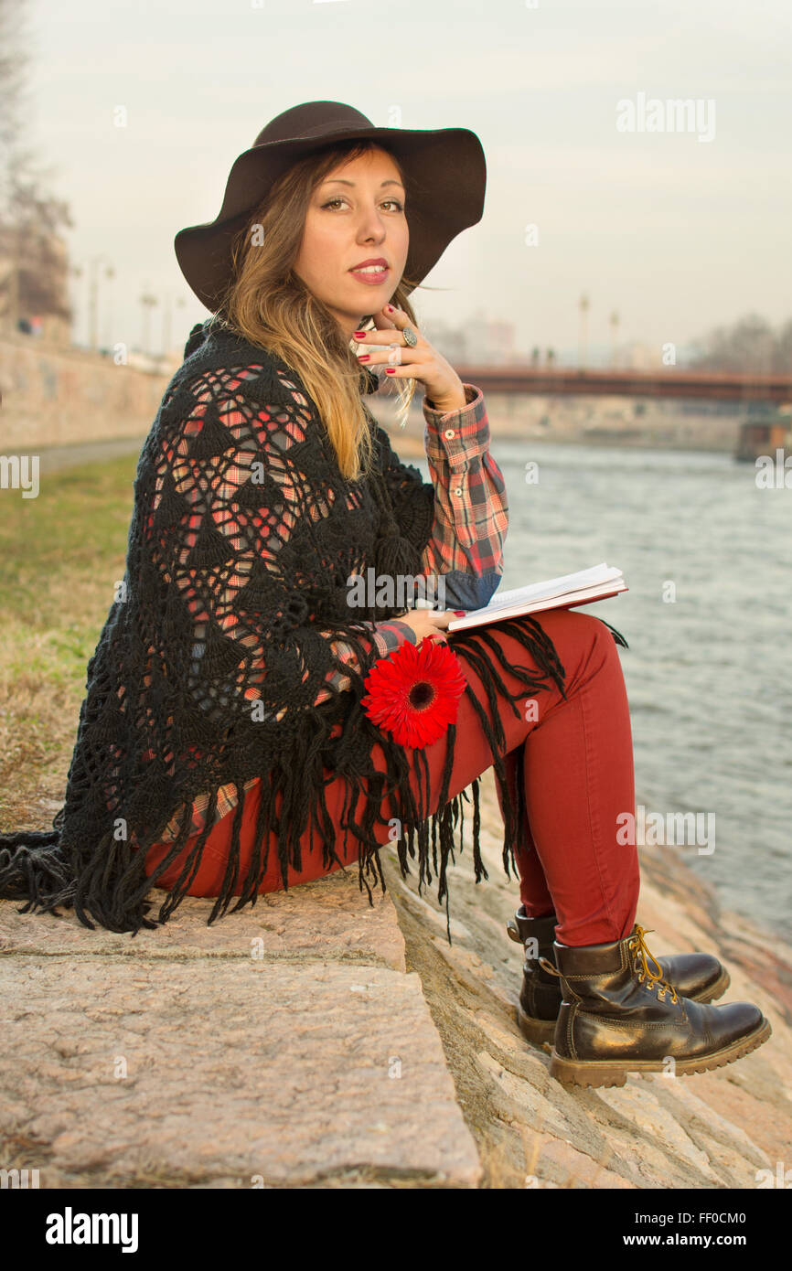 Bella bruna ragazza con un libro dalla banca di fiume Foto Stock