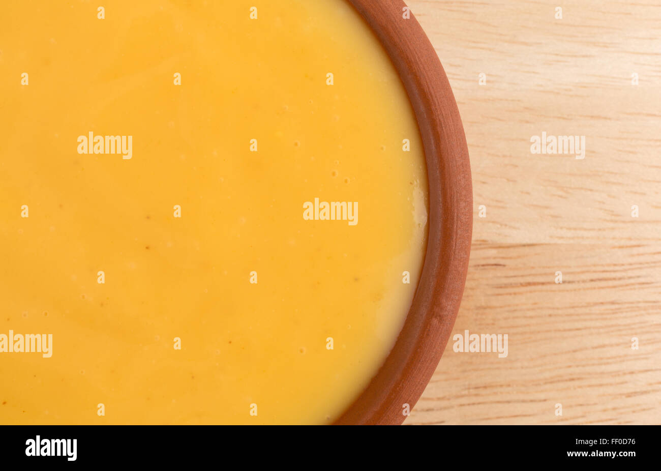 Inizio chiudi la vista di un piccolo piatto di miele mostarda condimento per insalata su una tavola di legno top illuminato con luce naturale. Foto Stock