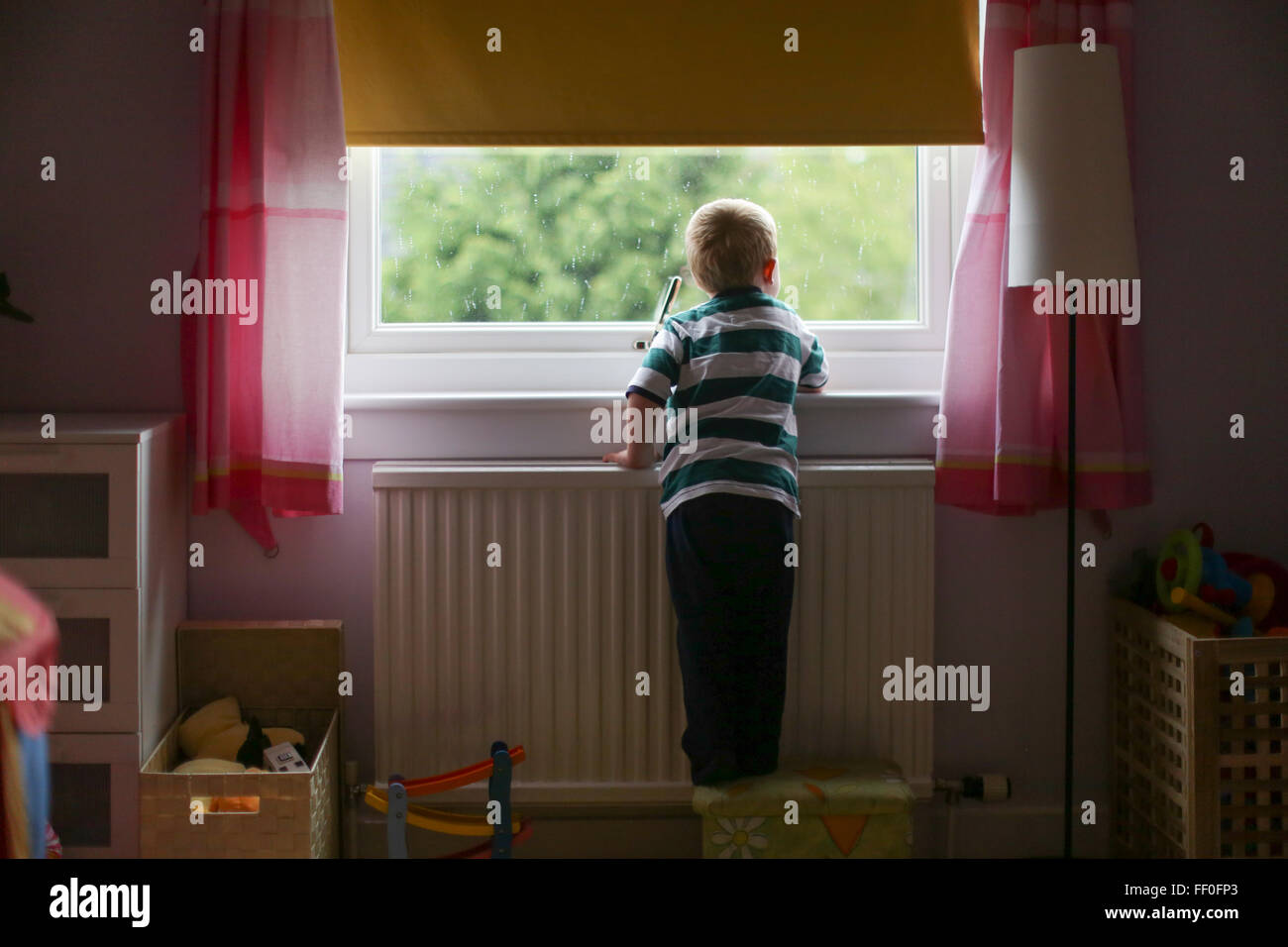 Bambino guardando fuori della finestra Foto Stock