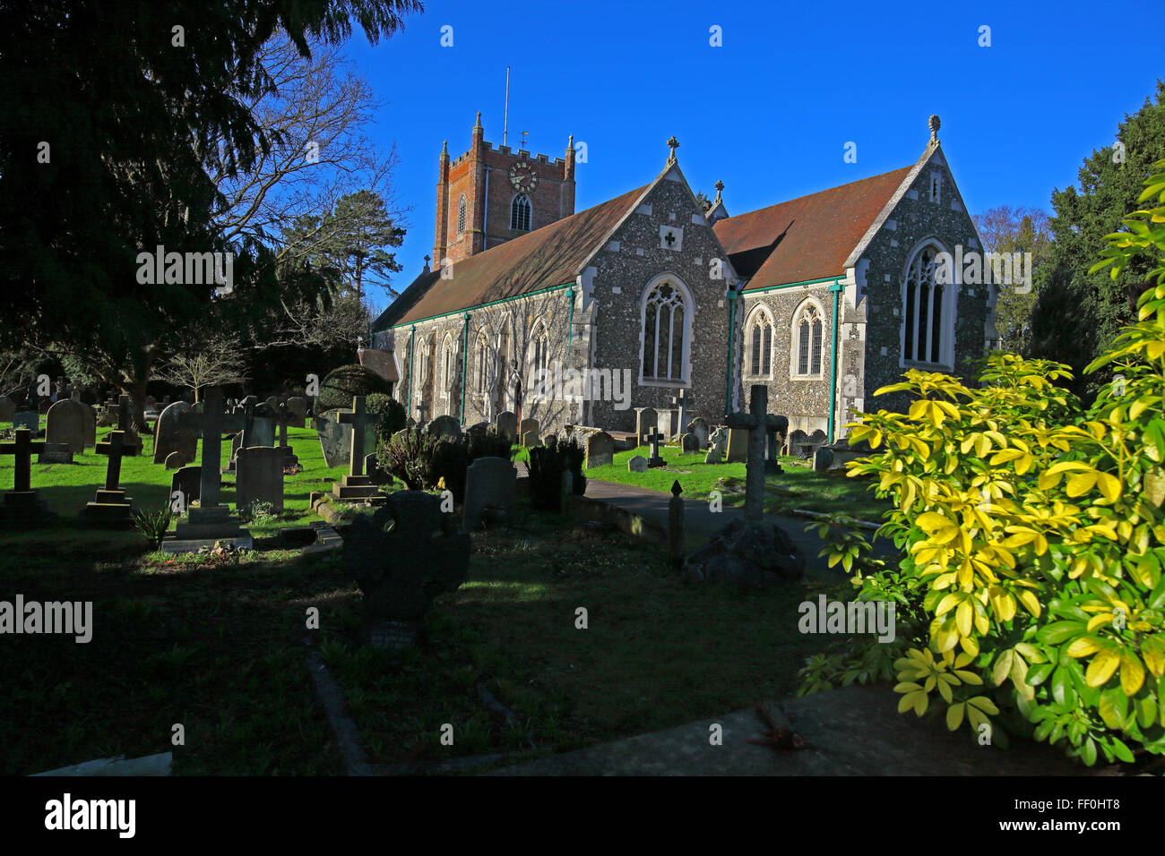 Una chiesa rurale con un clock tower e due sale principali set in a peaceful cimitero con perfettamente mantenuto erba e arbusti. Foto Stock