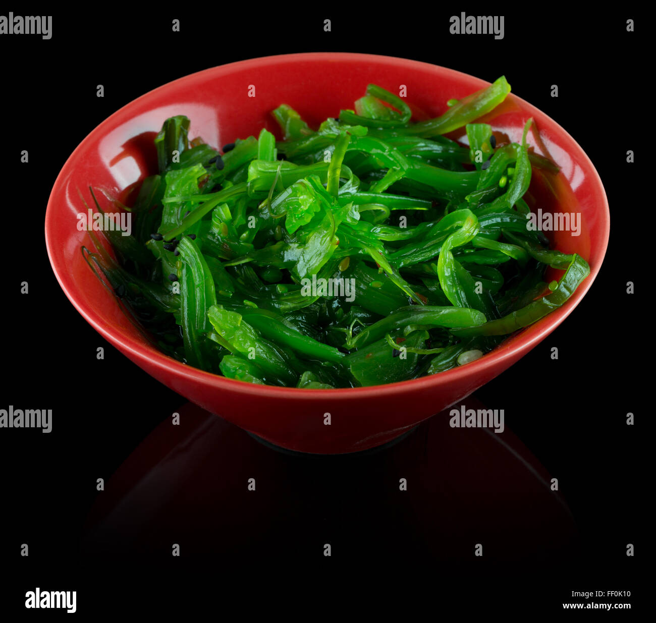 Alga verde insalata in targhetta rossa su uno sfondo nero. Foto Stock