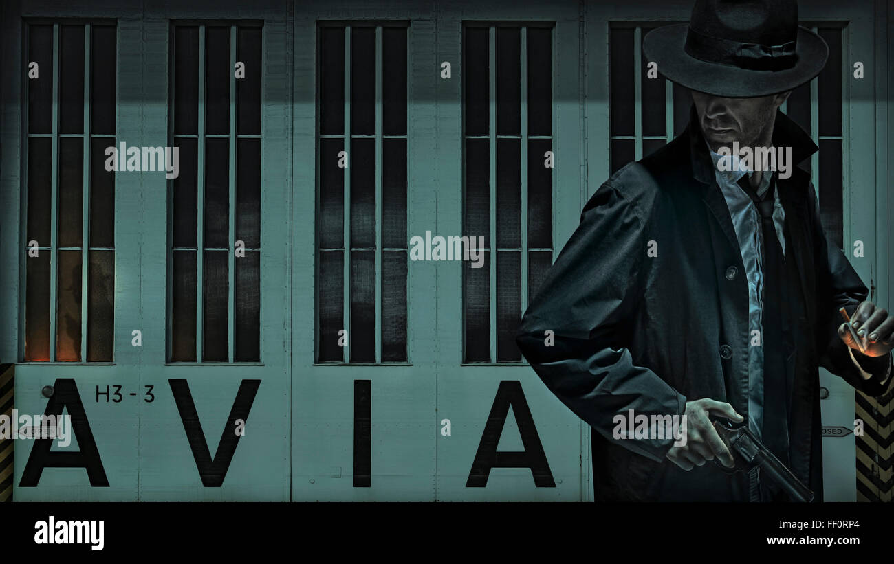 Uomo che porta pistola vicino aeroporto hangar Foto Stock