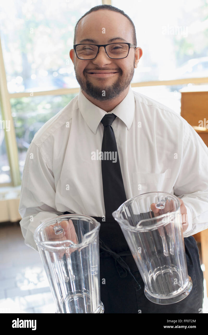 Razza mista server con la sindrome di down holding brocche in ristorante Foto Stock