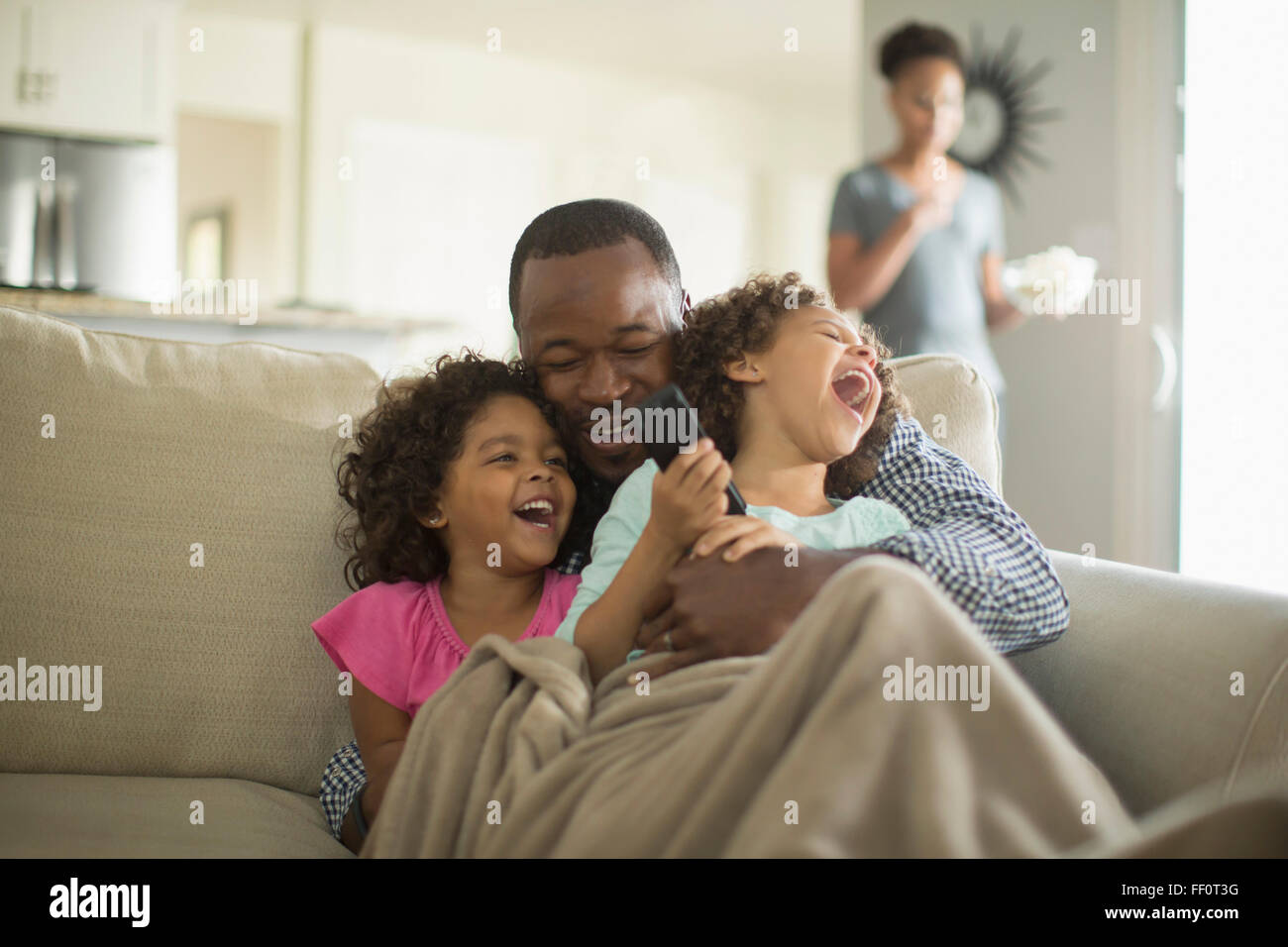 Padre e figlie giocando sul divano Foto Stock