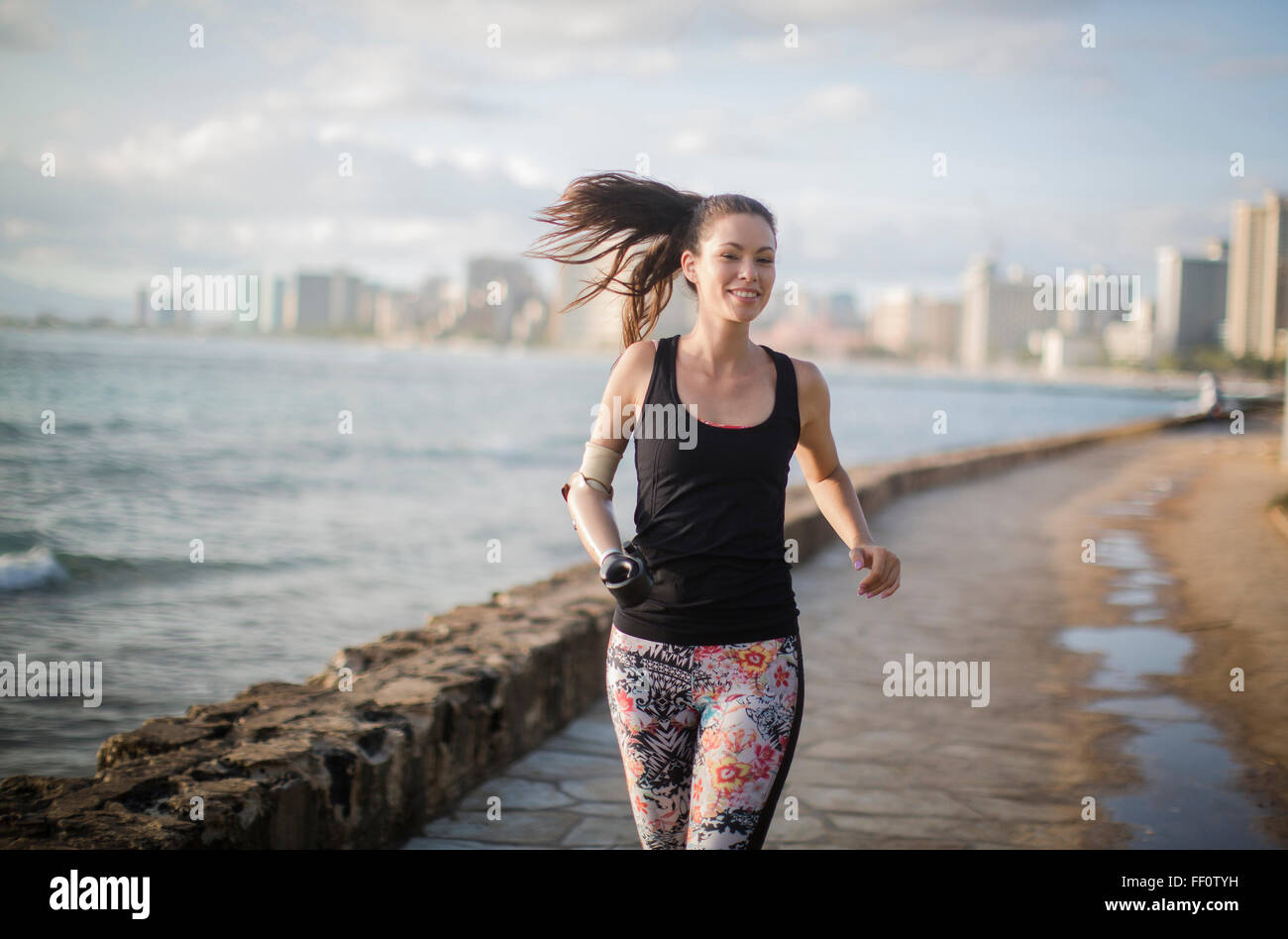 Razza mista amputato atleta jogging sul lungomare urbano Foto Stock