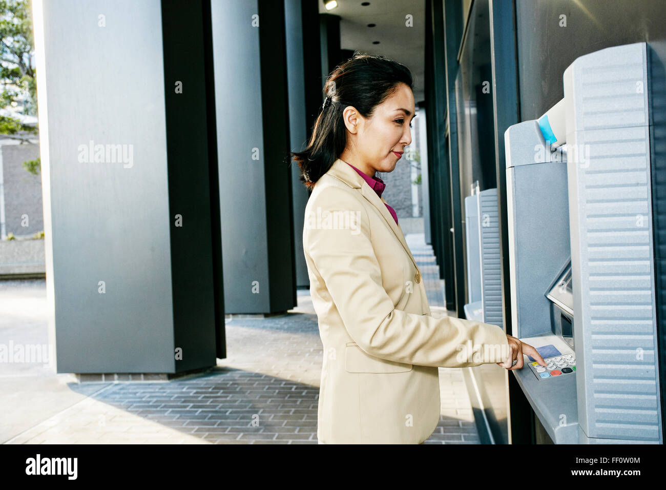 Asian imprenditrice utilizza ATM all'aperto Foto Stock