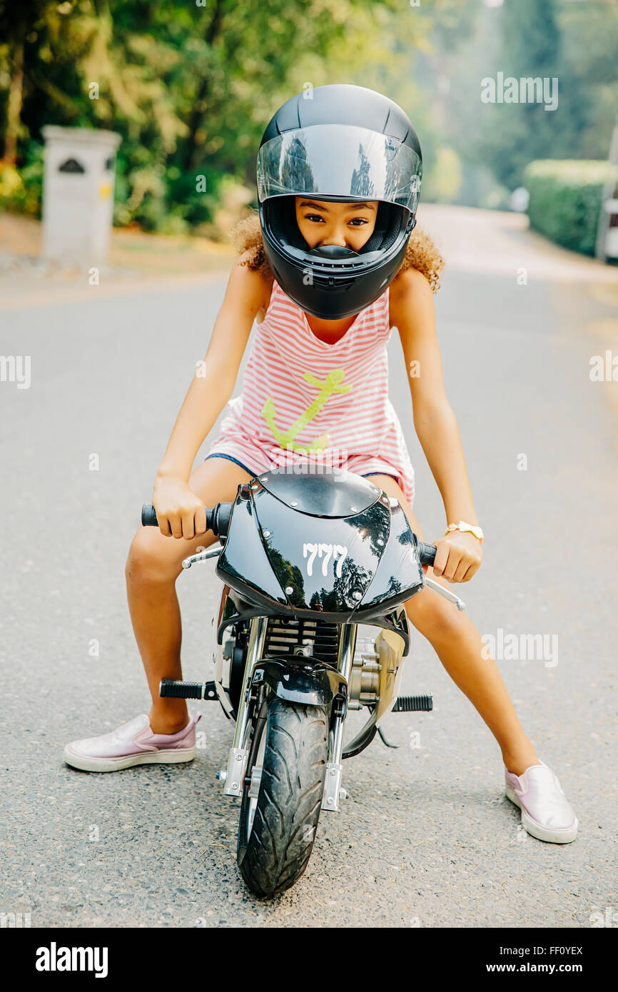 Razza mista ragazza seduta sulla motocicletta in miniatura Foto Stock