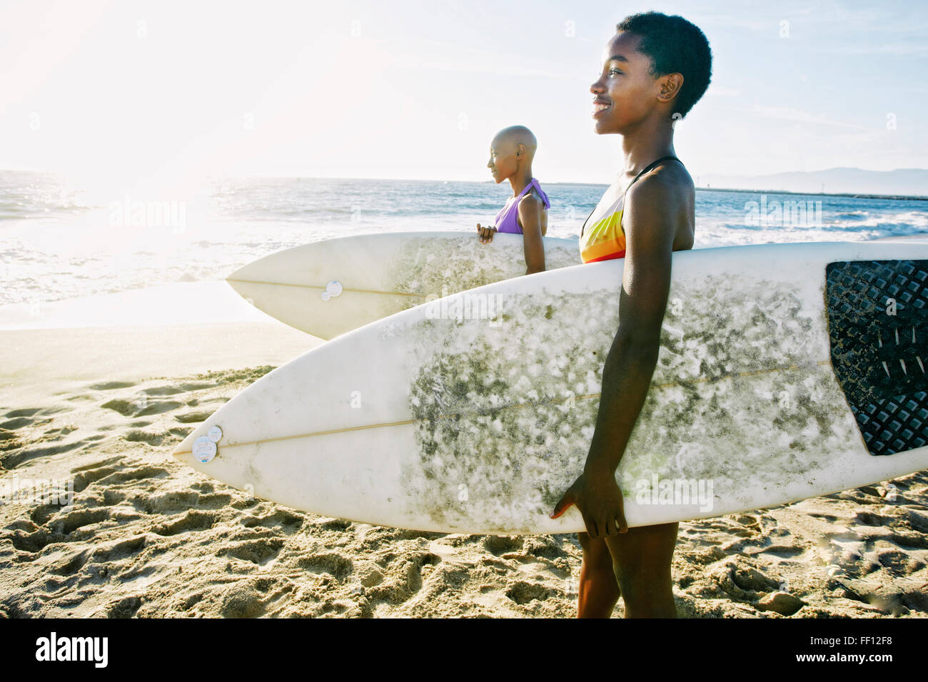 Il nero le donne che trasportano le tavole da surf in spiaggia Foto Stock