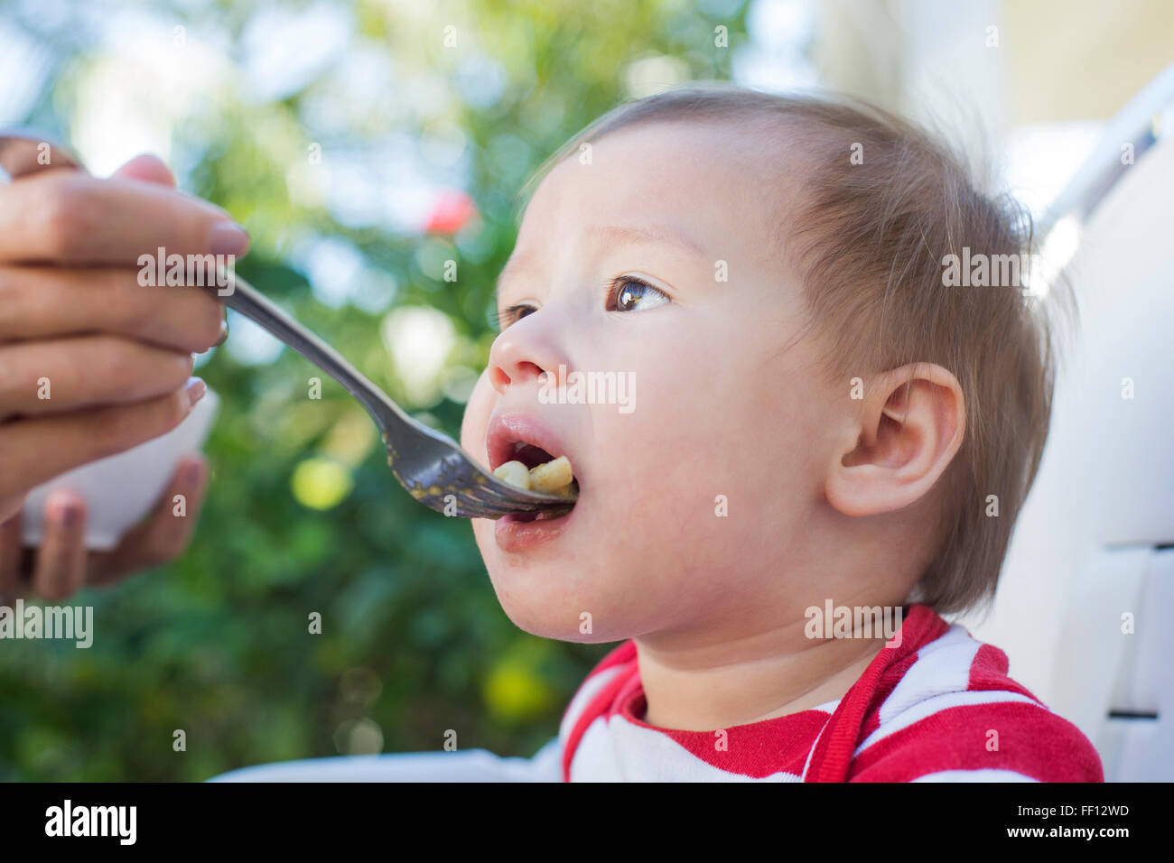 Razza mista madre del bambino di alimentazione esterni Foto Stock