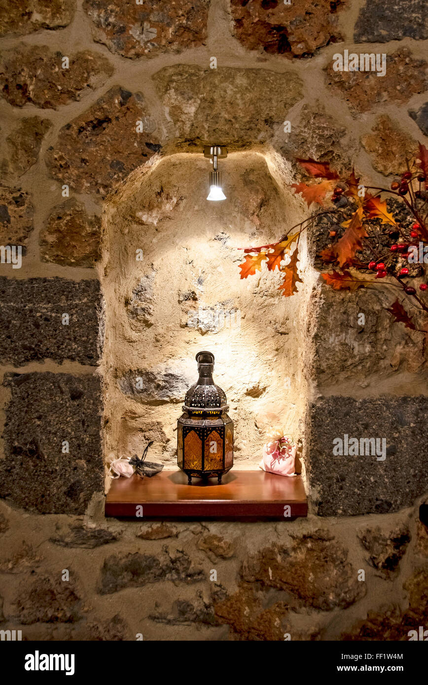 Illuminazione calda angolo decorato con una bella mano di oriental Lampada candela e foglie di acero sul muro di pietra Foto Stock