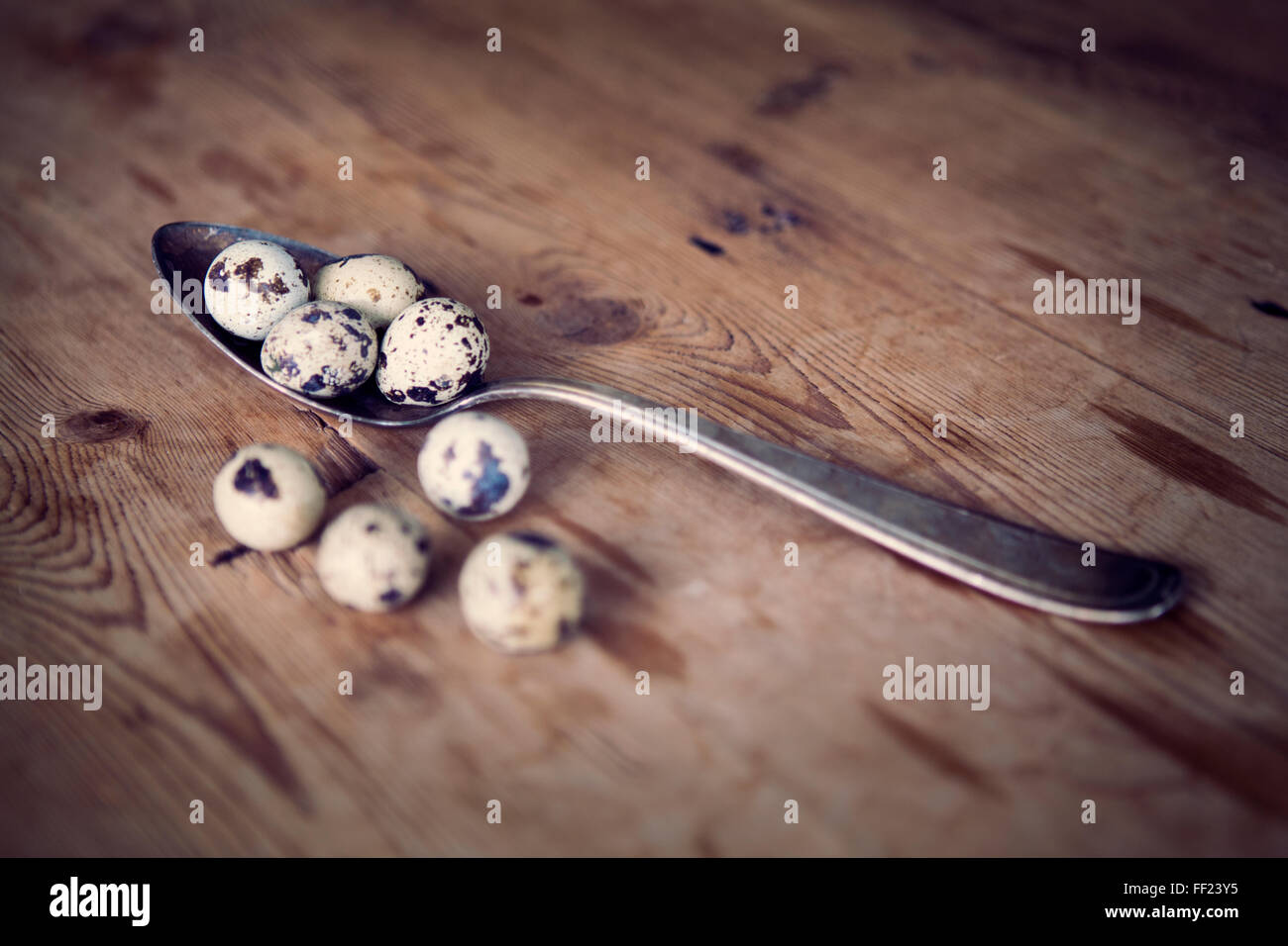 Vecchio cucchiaio d'argento con uova di quaglia su un tavolo di legno Foto Stock