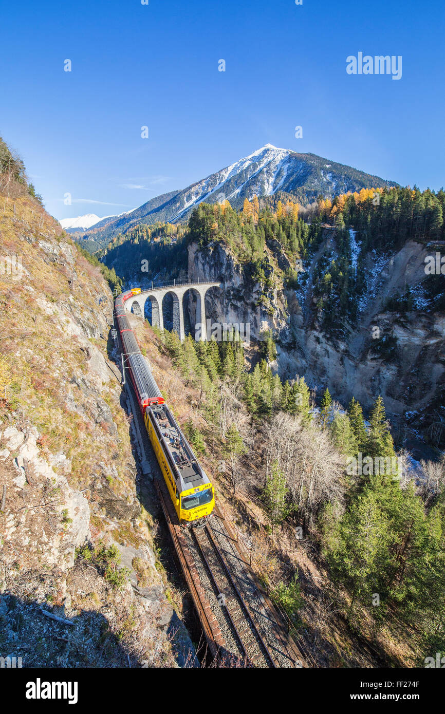 Bernina Express passa al di sopra del Landwasser Viadukt circondato da boschi colorati del Cantone dei Grigioni, Svizzera, Europa Foto Stock