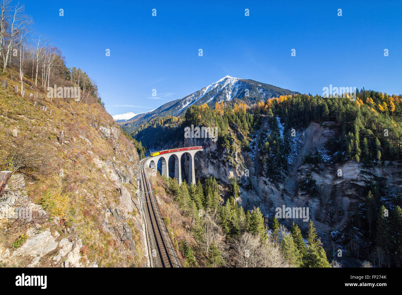 Bernina Express passa al di sopra del Landwasser Viadukt circondato da boschi colorati del Cantone dei Grigioni, Svizzera, Europa Foto Stock