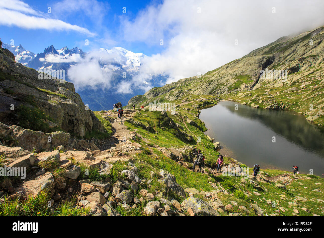 Nuvole basse e la nebbia attorno a delle Grandes Jorasses e Mont Blanc mentre gli escursionisti procedere sul Lac De Cheserys, Haute Savoie, sulle Alpi francesi Foto Stock
