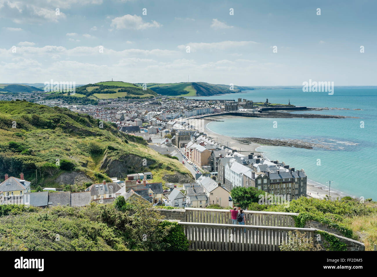 Un giovane in piedi su un ponte guardando verso il basso sulla spiaggia resort di Aberystwyth. Foto Stock