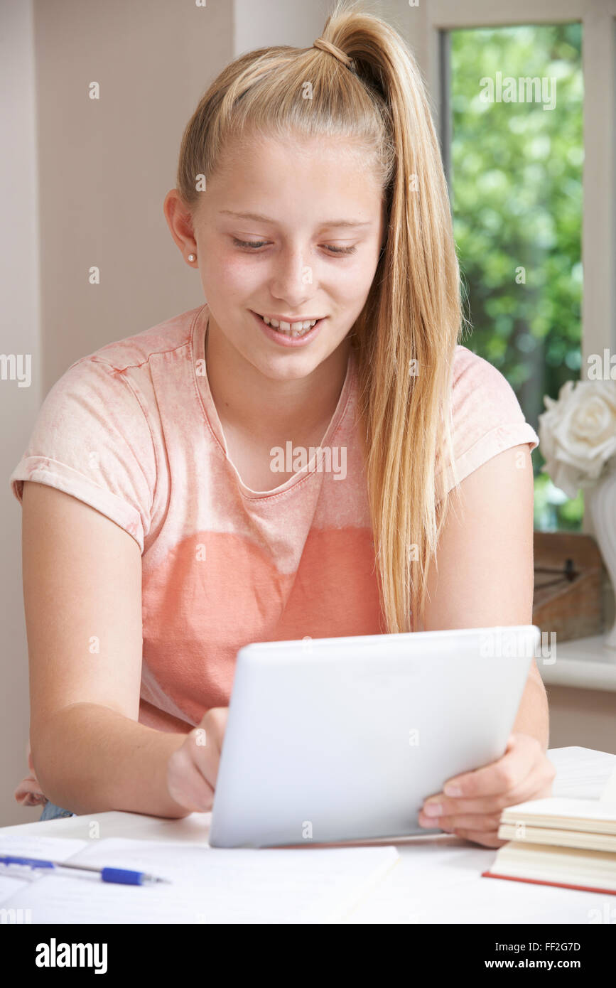 Ragazza adolescente facendo i compiti utilizzando tavoletta digitale Foto Stock