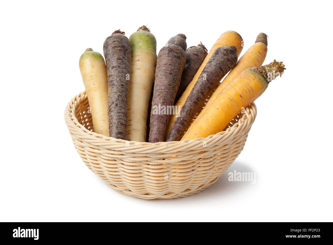 Crudo fresco nero, bianco e giallo le carote in un cesto su sfondo bianco Foto Stock