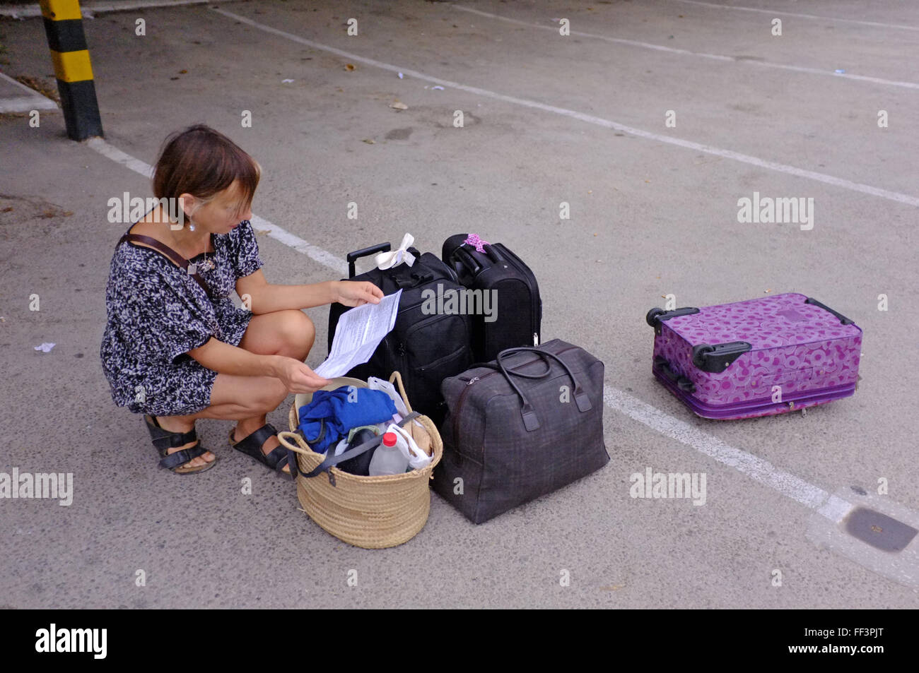 Un turista femminile guardando un autobus orari con bagagli sparsi intorno a una stazione degli autobus in Spagna. Foto Stock