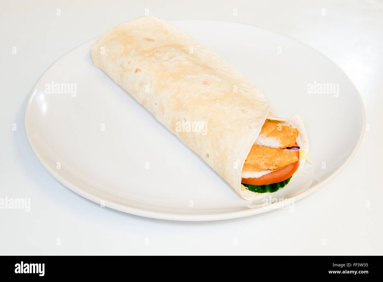 Pollo croccante e insalata in una tortilla avvolgere su di una piastra Foto Stock