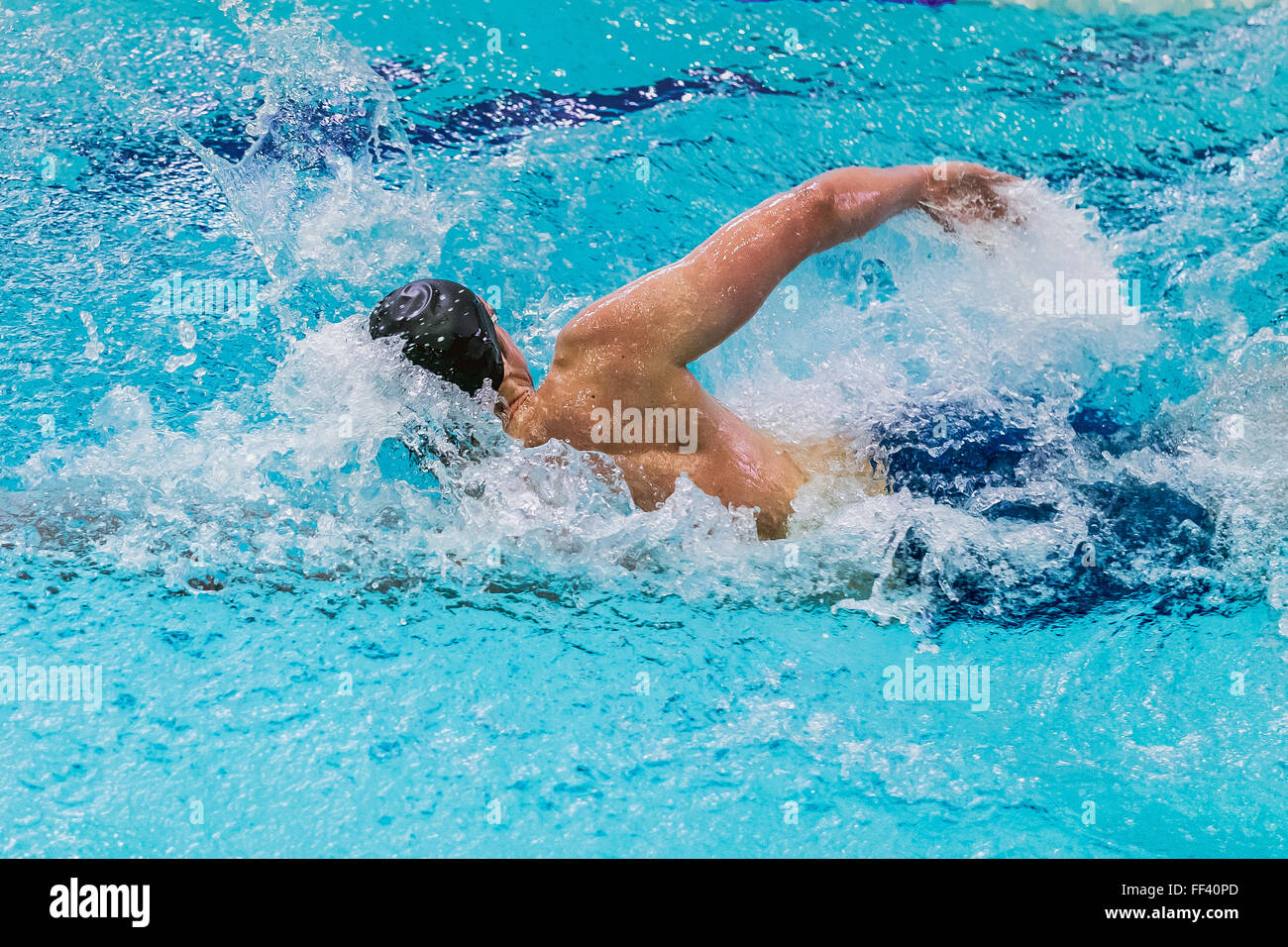 Giovane atleta maschio di freestyle di nuoto in piscina durante la concorrenza Foto Stock