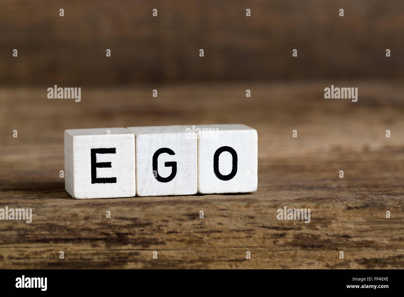 La parola ego scritto in cubi su uno sfondo di legno Foto Stock