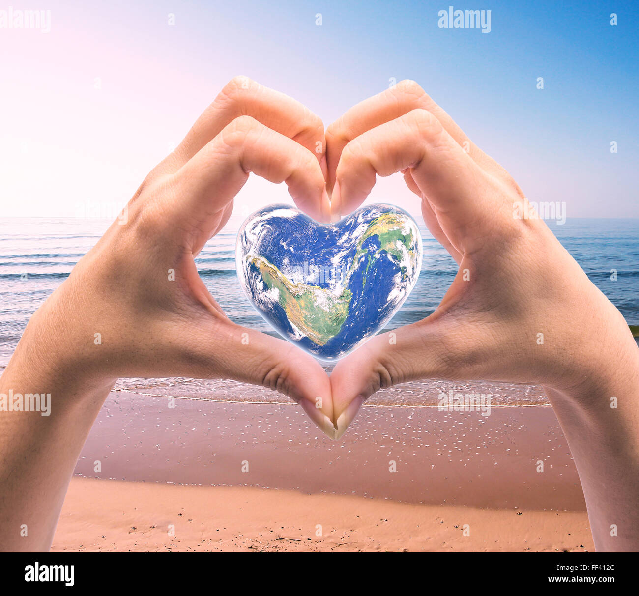 Mondo in forma di cuore con sopra le donne le mani umane su sfocato sfondo naturale blu turchese ciano tree e sky: World Heart hea Foto Stock