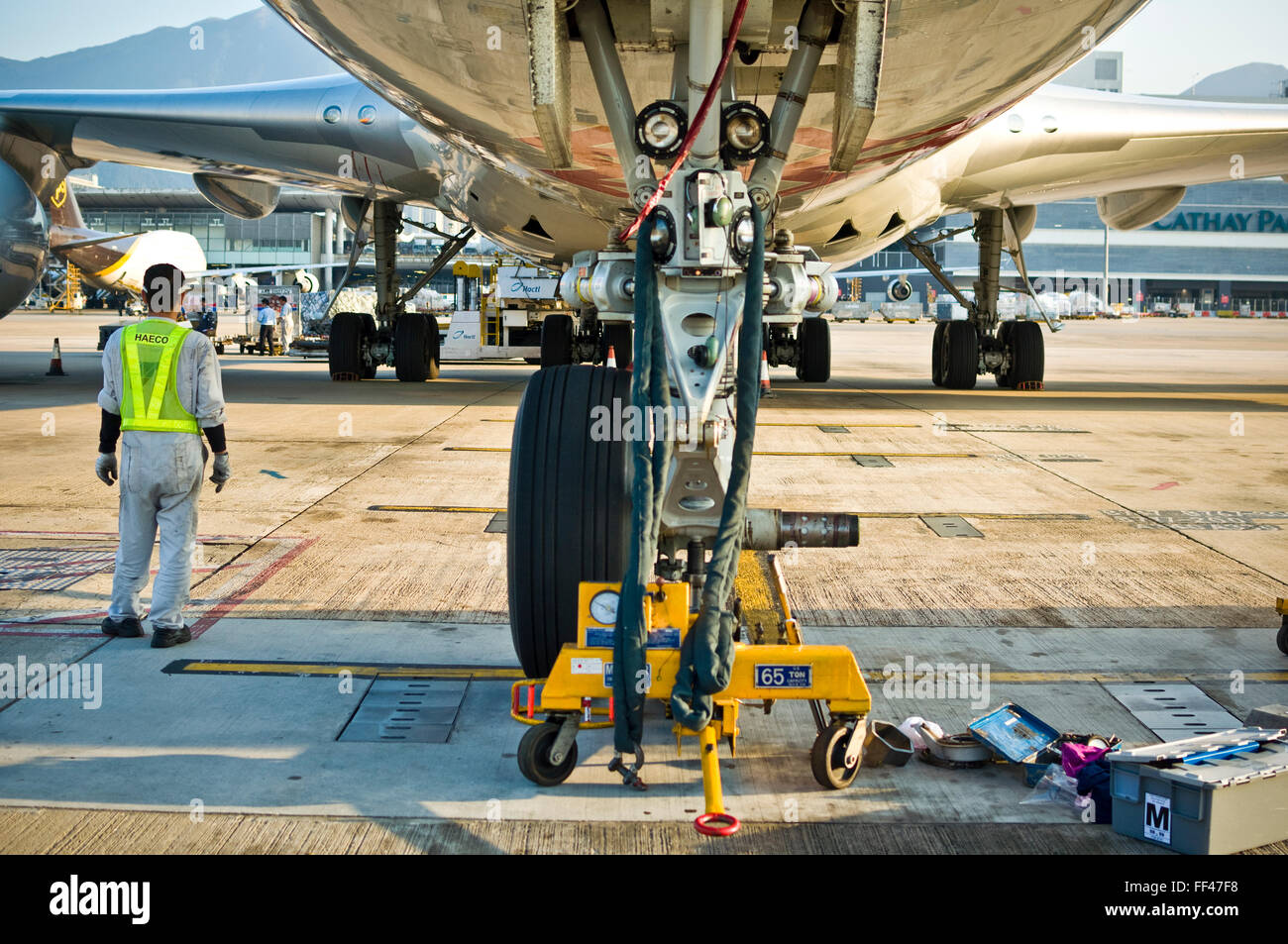 Modifica nosewheel su un Boeing 747-8 a hongkong aeroporto. jacklift 65t tecnico di manutenzione di aeromobili Foto Stock