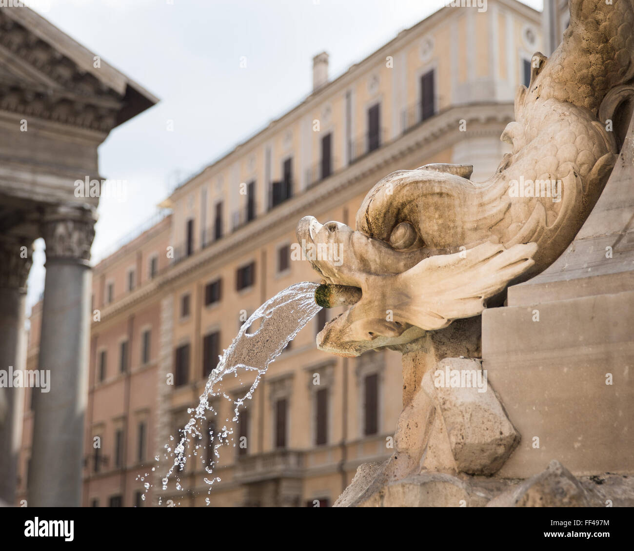 Roman fontana scolpita in forma di pesce. Il fuoco selettivo sulla fontana. Un angolo del Pantheon è visibile. Foto Stock