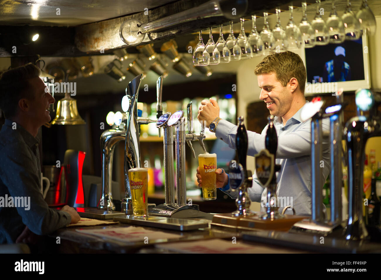 Un barman tirando una pinta di birra in un tradizionale pub inglese Foto Stock